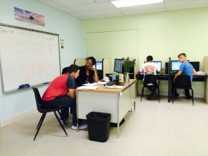 Math teacher Kiesha Jackson helps one student at Palm Acres Charter High School while others complete online coursework.